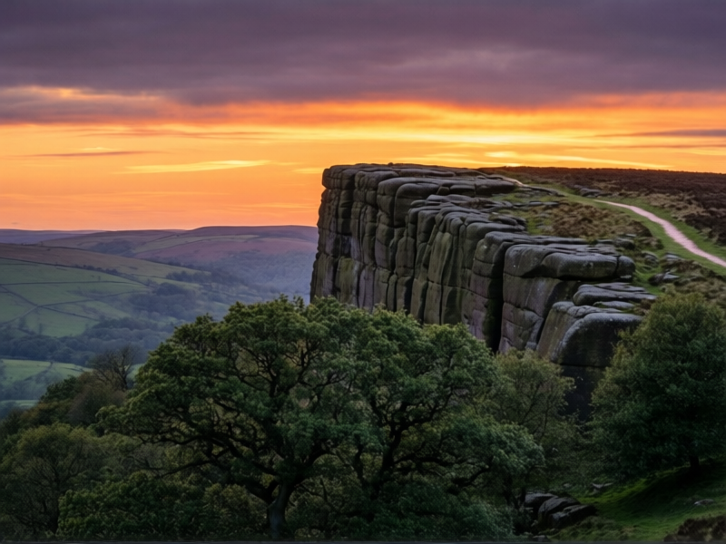 Stanage Edge in the Peak District, vast sandstone gritstone plateau rising from rolling Derbyshire countryside at sunset